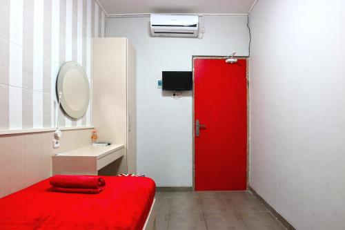 a red door in a small room with a red bed at Kamariska Hostel in Sedati