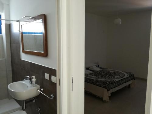 bagno con lavandino e letto con specchio di Mediterranea Guesthouse B&B a Portopalo