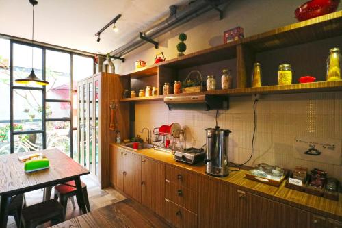 a kitchen with wooden cabinets and a table and a counter at Kamariska Hostel in Sedati