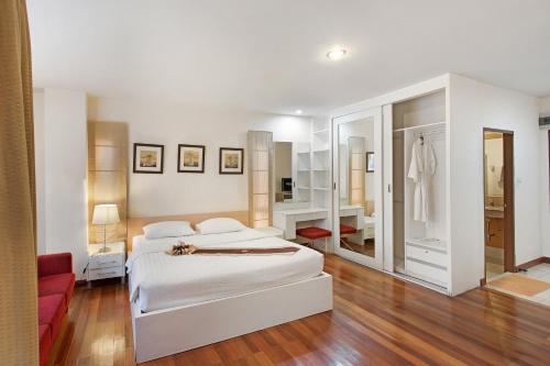 a white bedroom with a bed and a red couch at C-House & Residence Hotel Amata City in Pluak Daeng