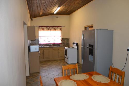 a kitchen with a table and a refrigerator at Esmarline Lodge in Brits