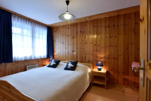 1 dormitorio con cama blanca y paredes de madera en Apartment Batteuse en Grimentz