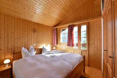 a bedroom with a bed with white sheets and a window at Chalet Diana in Grimentz