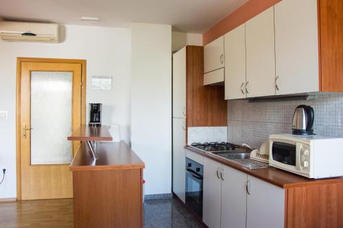 a kitchen with white cabinets and a microwave at Apartments Sv. Jelena 2 in Pag