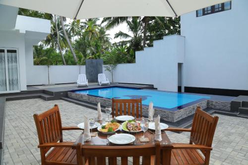 a dining table and chairs in front of a swimming pool at Sethum Villa Plus in Unawatuna
