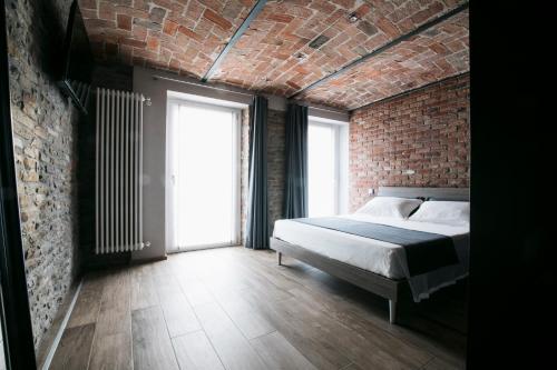 a bedroom with a bed and a brick wall at Villa Barbero Alba in Mango