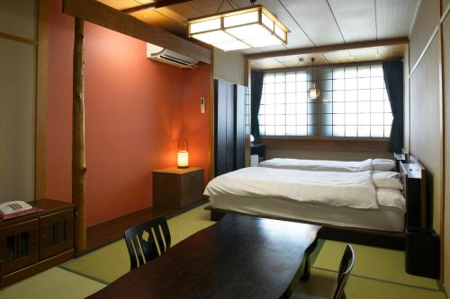 青森市にある宿屋 つばきのベッドルーム1室(ベッド1台、テーブル、椅子付)