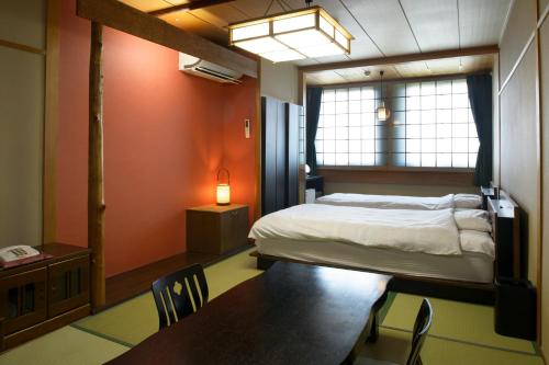 1 dormitorio con 1 cama, mesa y sillas en Yadoya Tsubaki en Aomori