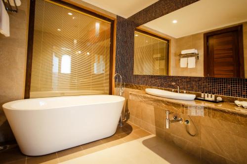 een badkamer met een bad, een wastafel en een spiegel bij Anaklia Resort by Pratap's Signature in Anaklia