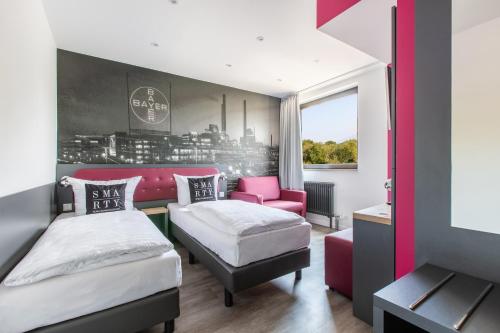 a bedroom with two beds and a pink chair at SMARTY Leichlingen-Cologne - KONTAKTLOSER SELF CHECK-IN in Leichlingen