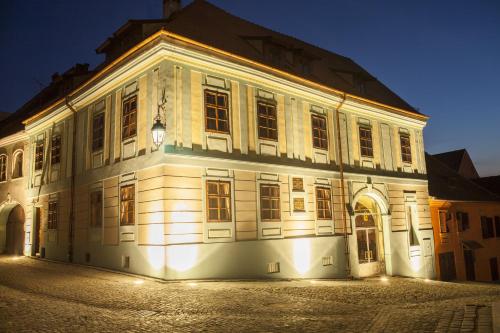 een groot wit gebouw met 's nachts verlichting bij Casa Georgius Krauss Sighisoara in Sighişoara