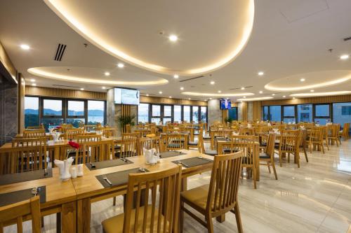 a restaurant with wooden tables and chairs and windows at Xavia Hotel in Nha Trang