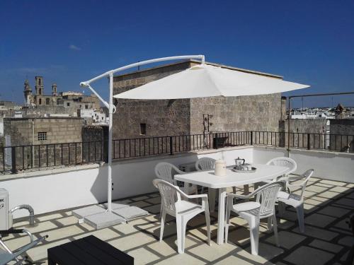 una mesa blanca y sillas en un balcón con sombrilla en Casa Lulù, en Presicce