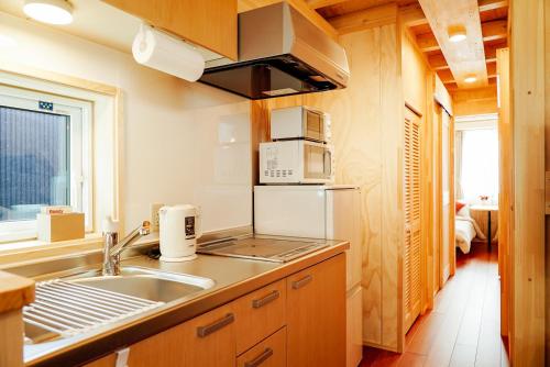 La cuisine est équipée d'un évier et d'un réfrigérateur. dans l'établissement Jstyle STAY Furano, à Furano