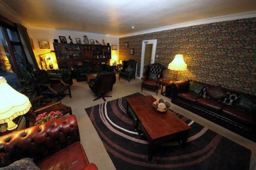 a living room with leather furniture and a brick wall at Stronchreggan View Guest House in Fort William