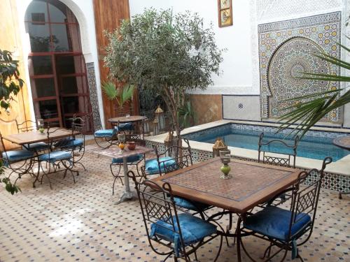 eine Terrasse mit Tischen und Stühlen sowie einem Pool in der Unterkunft Riad Attarine in Fès