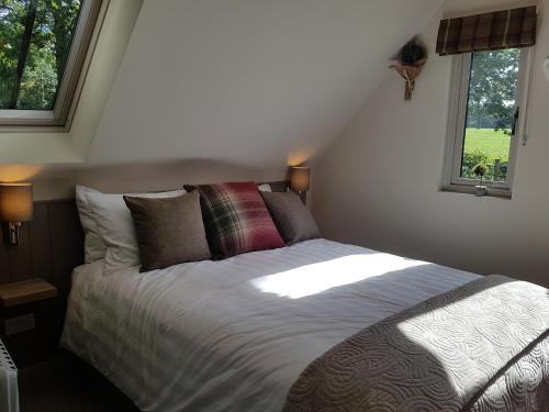 a bed in a bedroom with two windows at The Barn Tarporley in Tarporley