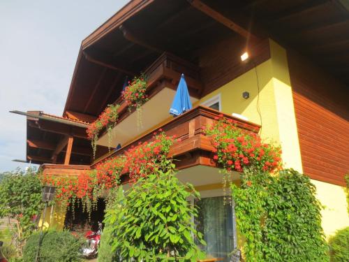 a building with a balcony with flowers and a blue umbrella at Hotel Alp Inn - Chiemgaukarte inclusive in Ruhpolding