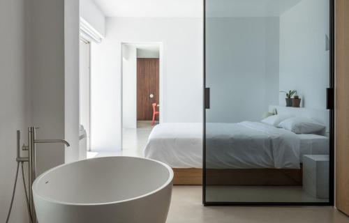 baño blanco con bañera y cama en Santorini Heights, en Pirgos
