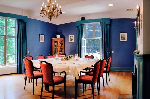 a dining room with a table and chairs and blue walls at Bilderberg Kasteel Vaalsbroek in Vaals