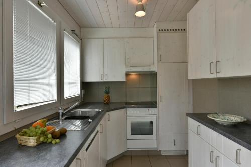 格里門茨的住宿－Chalet Mousseron，厨房配有白色橱柜和水槽,台面上备有水果