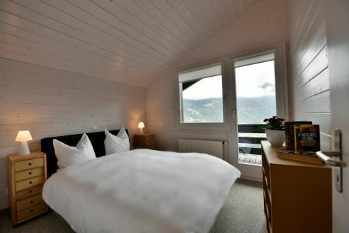 ein Schlafzimmer mit einem großen weißen Bett und einem Fenster in der Unterkunft Chalet Mousseron in Grimentz