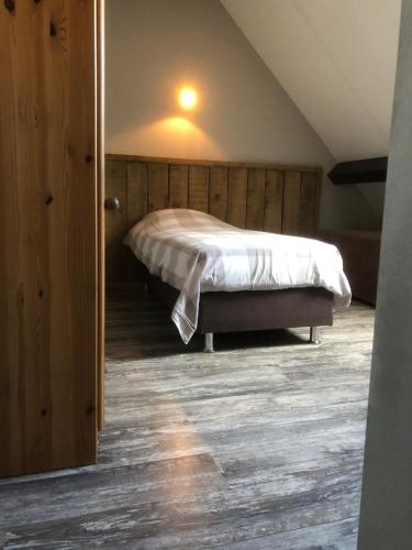 um quarto com uma cama num sótão em Bed & Breakfast de Bimd Hoeve em De Bus