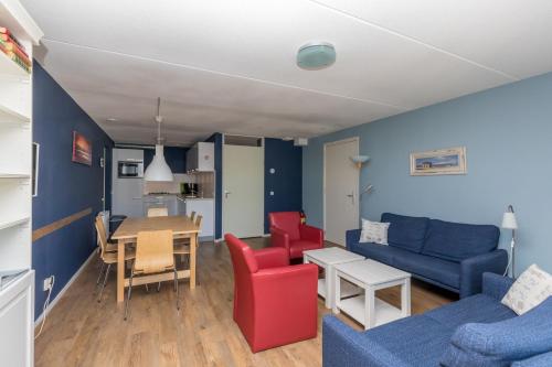 a living room with a blue couch and red chairs at Nautic Rentals - Marinapark Oude-Tonge in Oude-Tonge