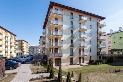 un edificio de apartamentos con coches aparcados en un aparcamiento en Apartments Świnoujście Center III by Renters, en Świnoujście