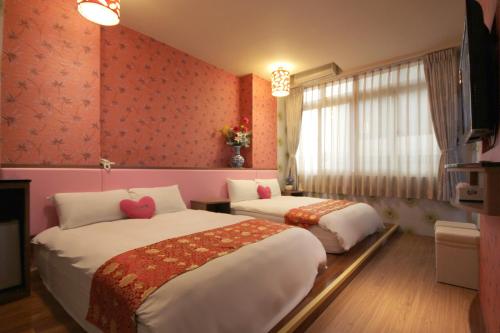two beds in a room with pink walls at 泉福潭暉民宿 in Yuchi