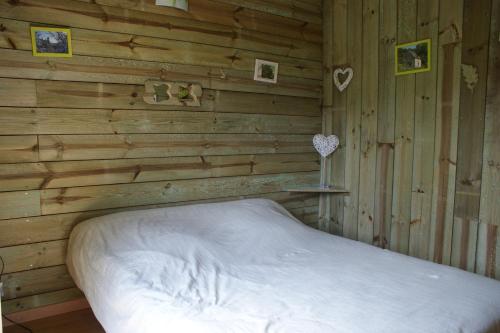Un dormitorio con una cama en una pared de madera. en Le gîte de Chomet, en La Tour-dʼAuvergne