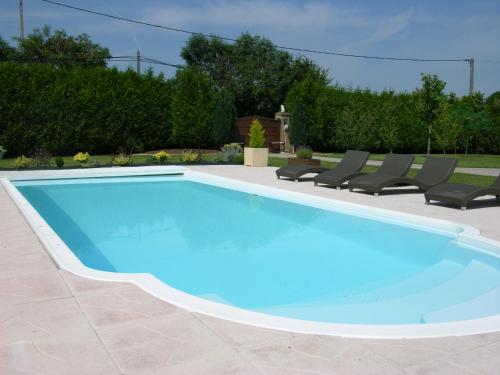 una gran piscina azul con sillas alrededor en Gîtes Les Colombages en Fatouville-Grestain