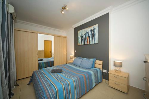 Schlafzimmer mit einem Bett mit blauer Decke in der Unterkunft BV7 - Bridge View Apartment in St Julian's