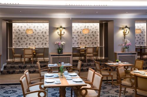 a dining room with tables and chairs and chandeliers at Le Littré in Paris