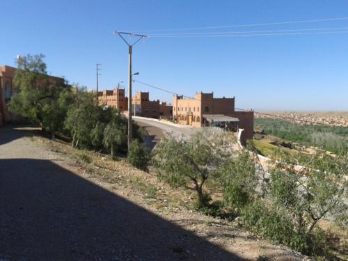 a road in the middle of a desert with buildings at Hotel Almanader in Boumalne