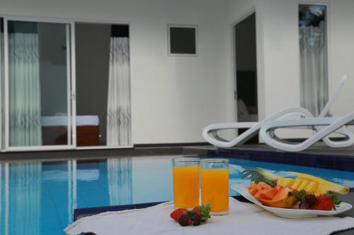a table with a plate of fruit and two glasses of juice at Sethum Villa Plus in Unawatuna