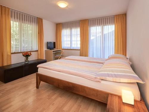 um quarto com uma cama grande num quarto com janelas em Haus Bor em Zermatt