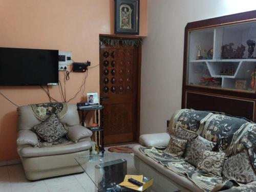 a living room with two chairs and a flat screen tv at Padmaa Hampi Villa in Hampi