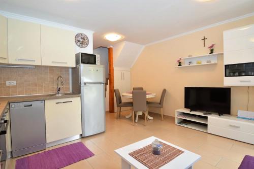 a kitchen with a refrigerator and a table with chairs at Apartment Hrasta in Vrana