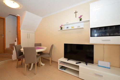 a dining room with a table and a tv at Apartment Hrasta in Vrana