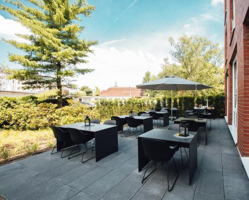 a patio with tables and chairs and an umbrella at HK Hotel Düsseldorf City in Düsseldorf