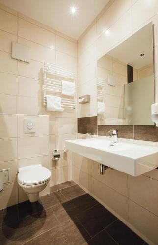 a bathroom with a sink and a toilet and a mirror at HK Hotel Düsseldorf City in Düsseldorf