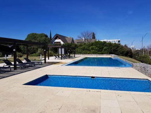 a swimming pool with blue water in a yard at Apart Altos del Virrey in Colonia del Sacramento