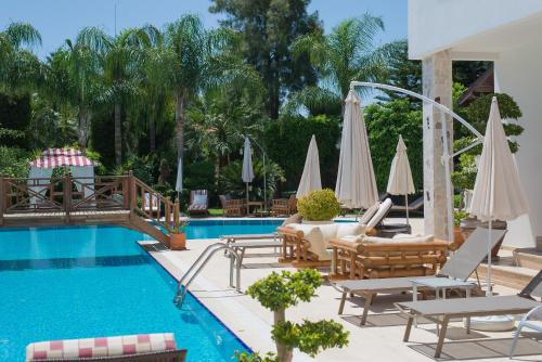 einen Pool mit Liegestühlen und Sonnenschirmen neben einem Pool in der Unterkunft Sofia Residence in Kemer