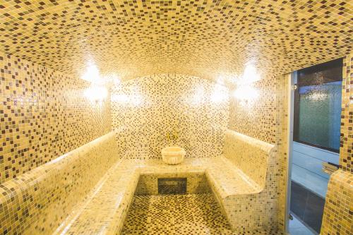 a tiled bathroom with a tub with a toilet in it at Emerald Hotel Baku in Baku