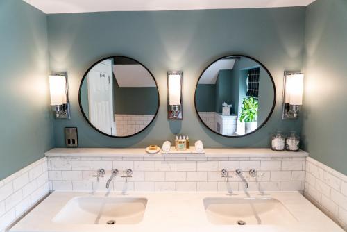 two sinks in a bathroom with two mirrors at Arrow Mill- Brunning and Price in Alcester