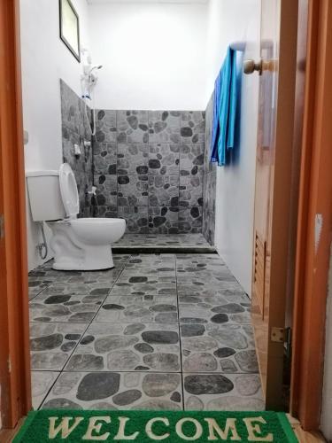 a bathroom with a toilet and a welcome mat on the floor at Andnindot garden resort in Anda