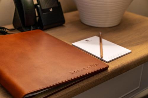 a brown notebook sitting on a desk with a pencil at Arrow Mill- Brunning and Price in Alcester