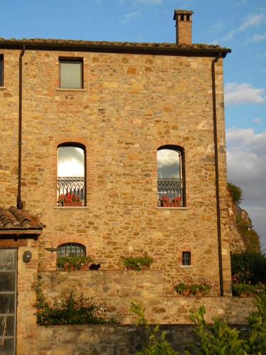 an old brick building with three windows on it at Agriturismo Tenuta il Tasso in Rapolano Terme