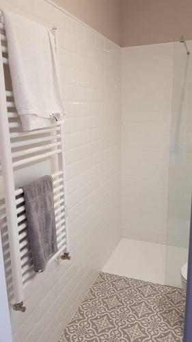 a white bathroom with a shower and a towel at La Casina del Cerecedo in León